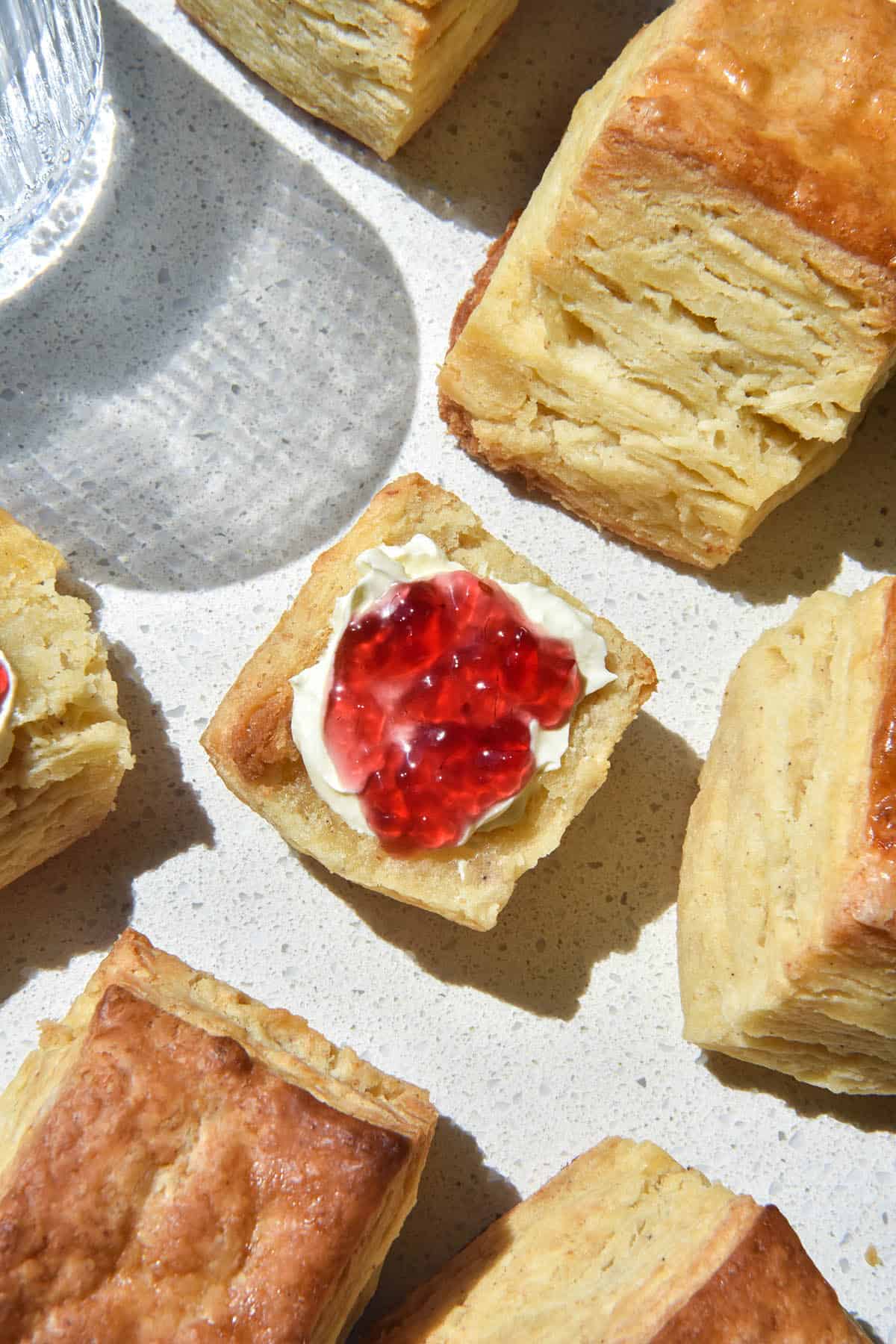 An aerial image of gluten free biscuits (American style) on a brightly lit white bench top.