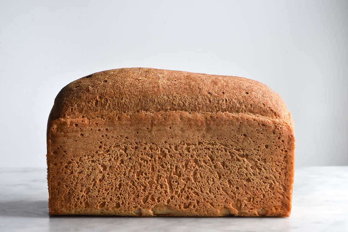 A side on view of a loaf of grain free bread against a white backdrop