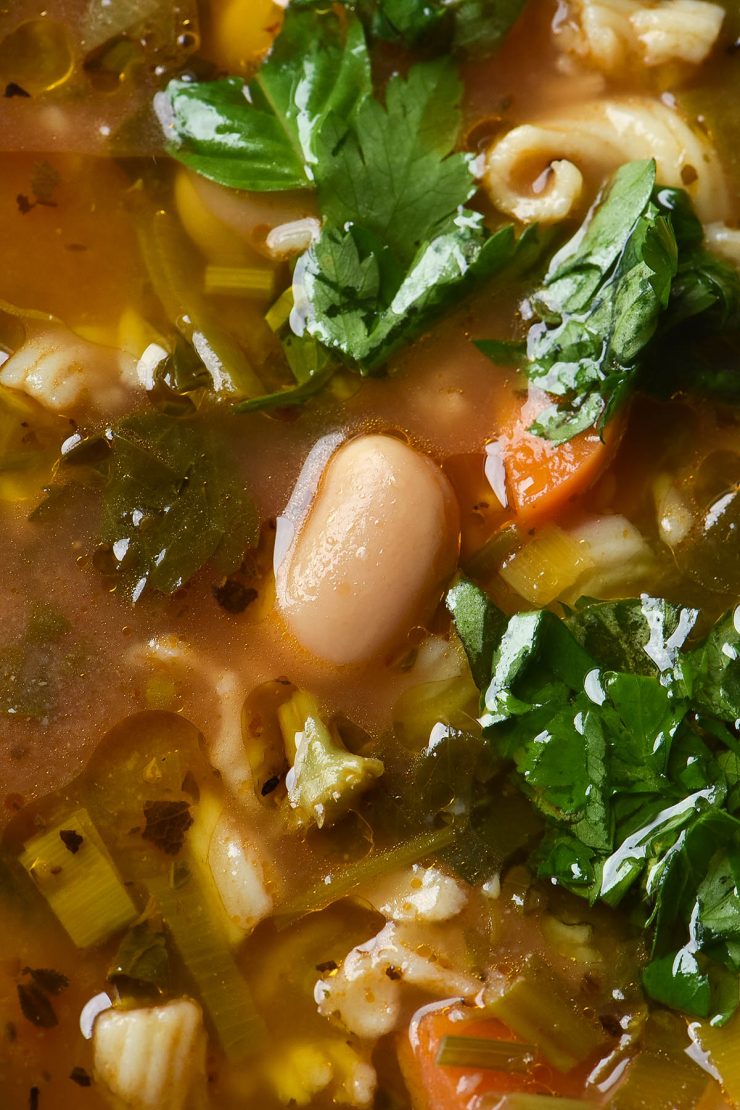 A macro close up view of a bean sitting in a low FODMAP broth based minestrone