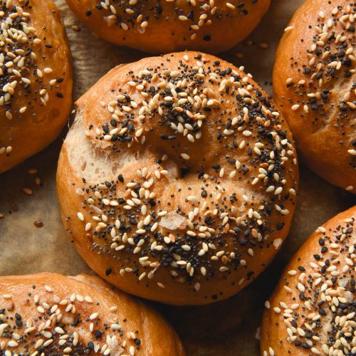 An aerial close up image of gluten free vegan bagels topped with low FODMAP everything bagel seasoning on a lined baking sheet