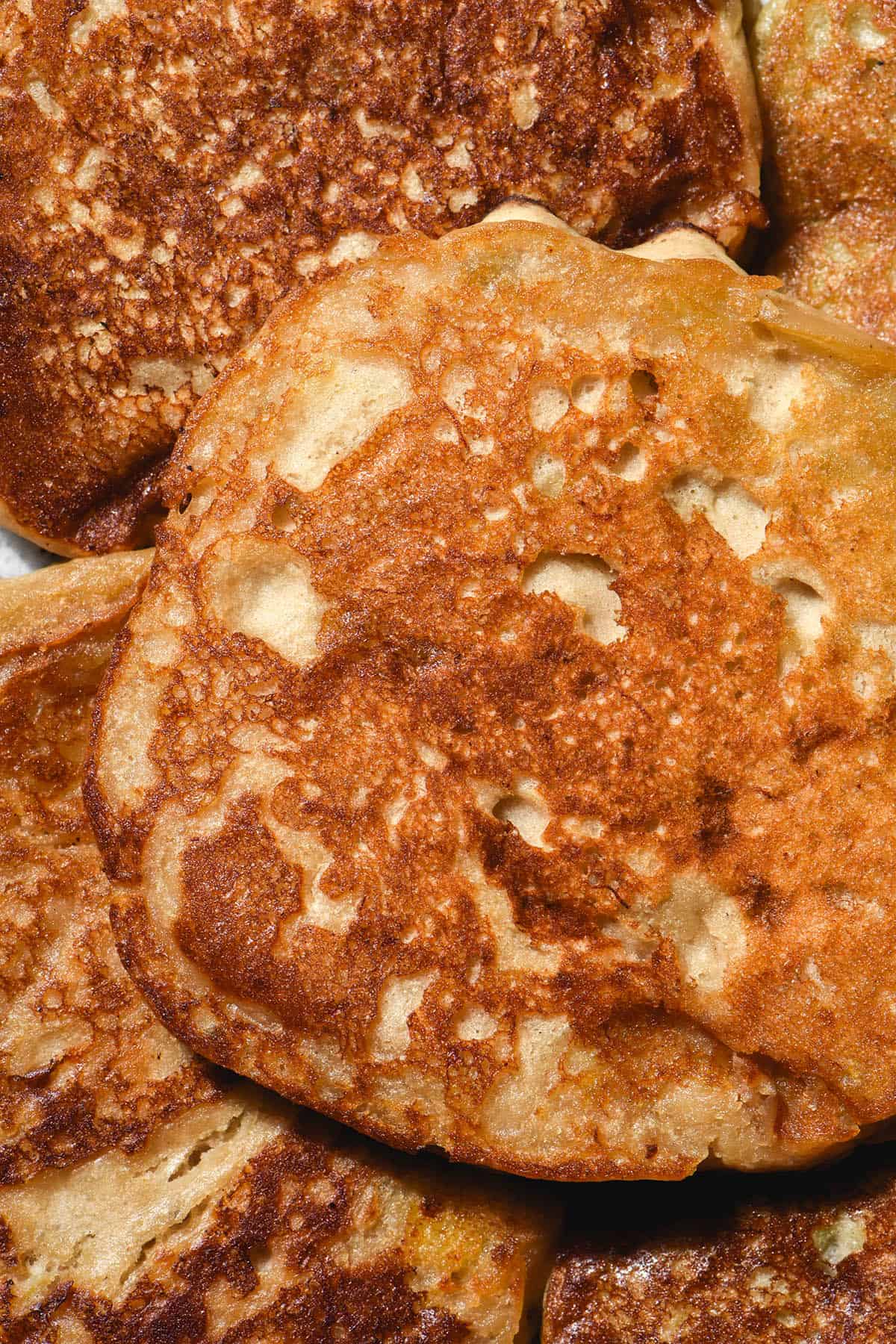 A close up macro image of a plate topped with golden brown vegan protein pancakes