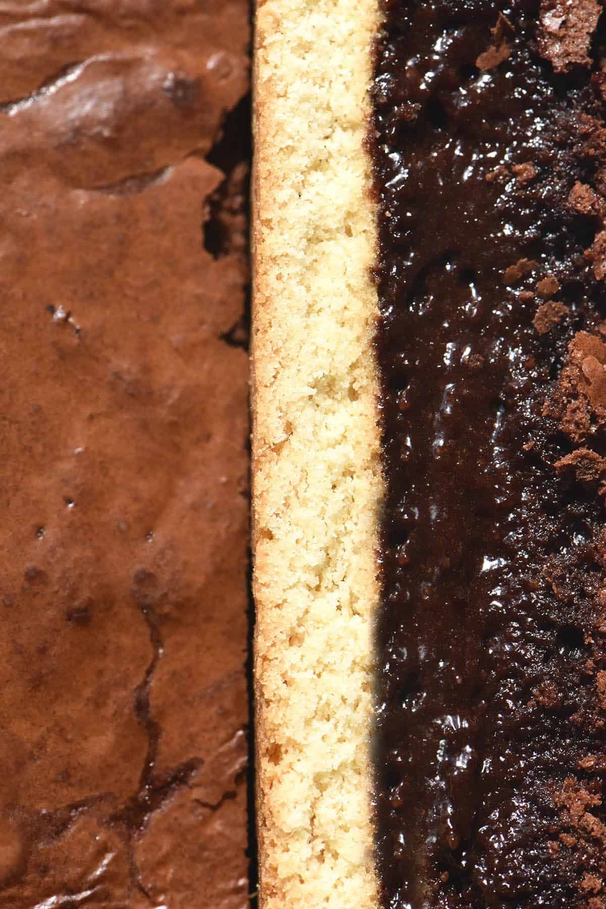 An aerial close up of a slice of shortbread brownie facing upwards, revealing the shortbread layer and gooey brownie underneath. The piece is propped up against the rest of the brownie, which sits crackly side up. 