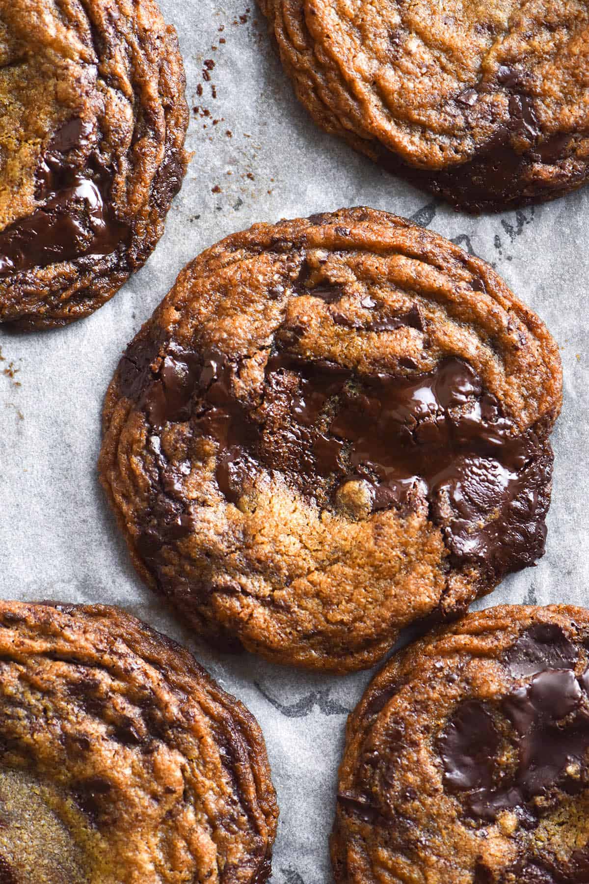 An aerial image of a baking tray of buckwheat chocolate chip cookies. The cookies are golden brown and studded with melty dark chocolate chunks. 