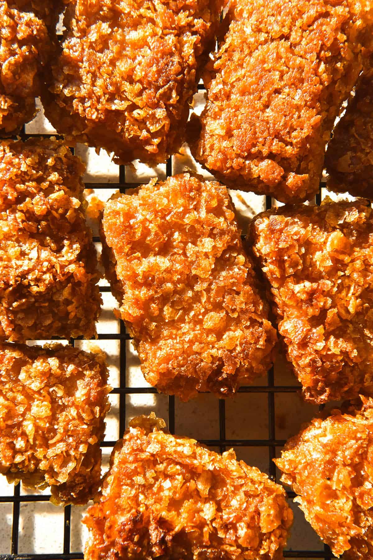 A brightly lit aerial close up image of gluten free tofu nuggets arranged casually on a cooling rack. 