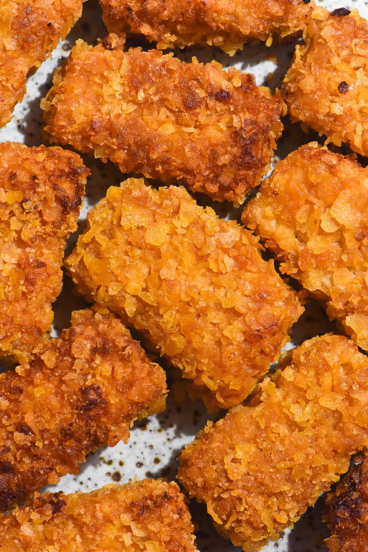 An aerial macro image of gluten free tofu nuggets on a white speckled ceramic plate