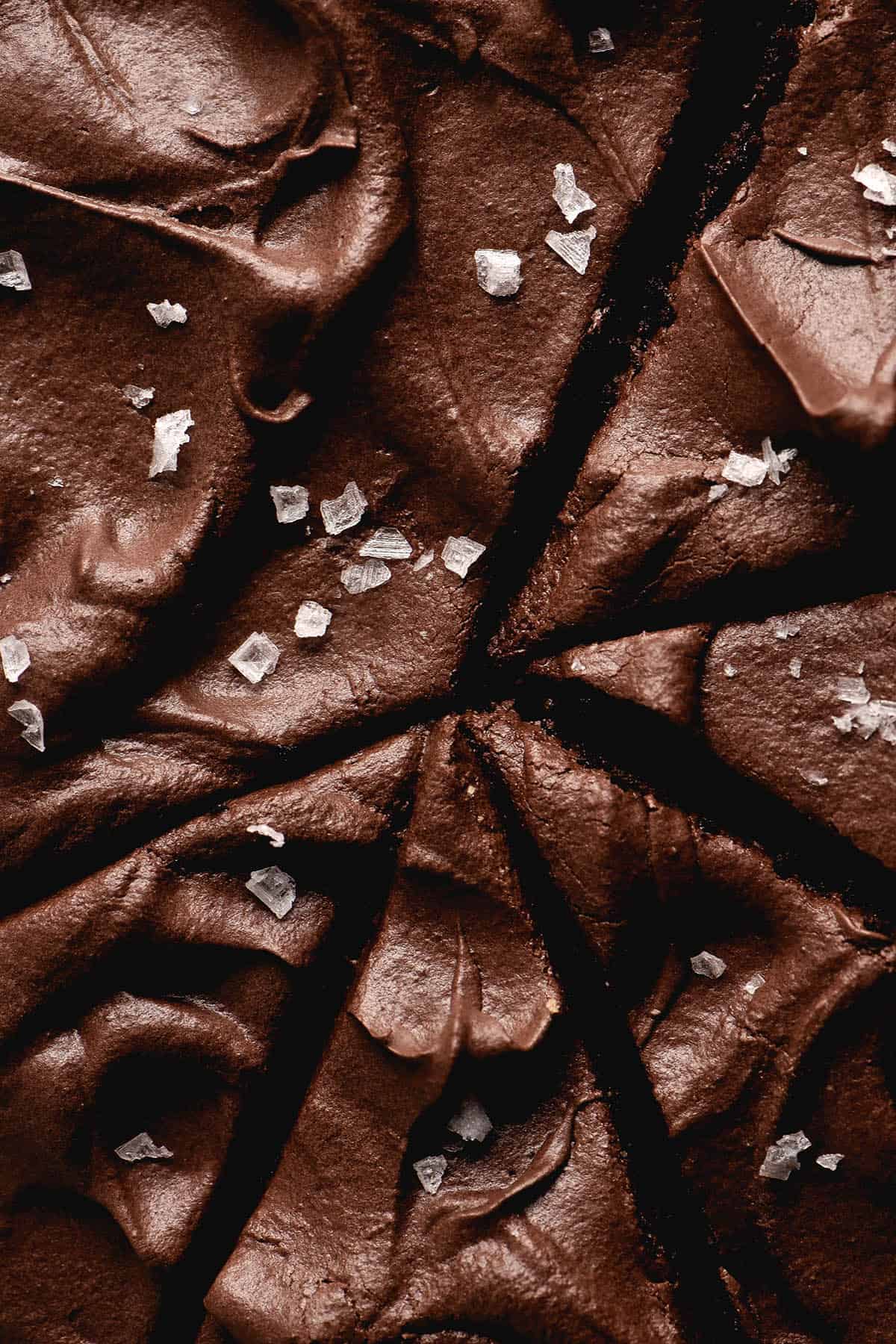 An aerial macro view of a gluten free chocolate cake iced with chocolate buttercream and finished with sea salt flakes