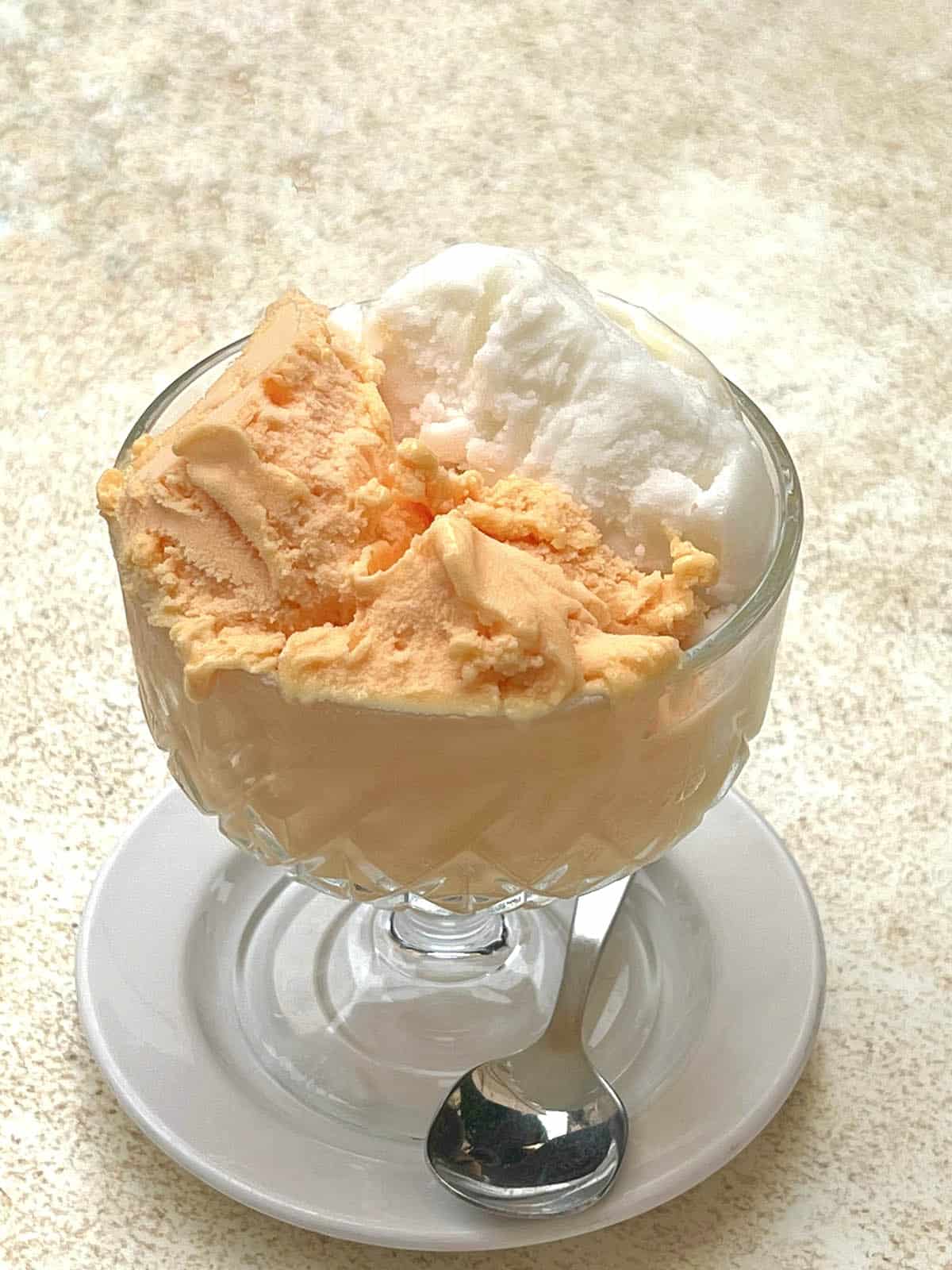 An image of a glass dessert cup filled with madarin and lemon gelato from Caffè Costanzo 