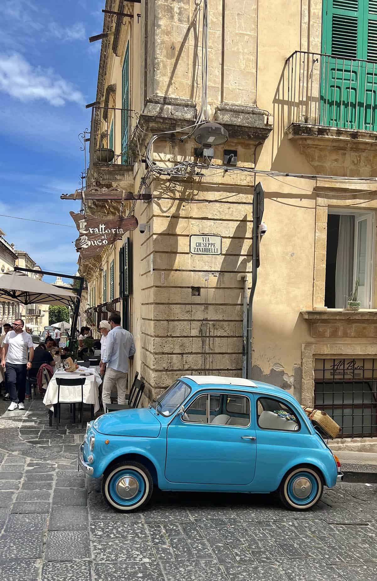 An image of an old blue Italian car on a street in Noto, Sicily.