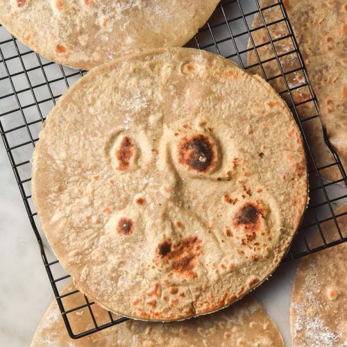 An aerial image of buckwheat wraps on a cooling rack atop a white marble table