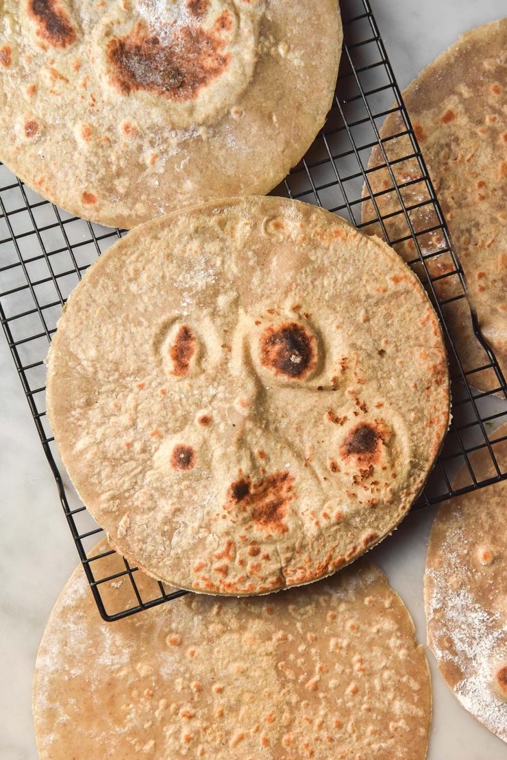 An aerial image of buckwheat wraps on a cooling rack atop a white marble table