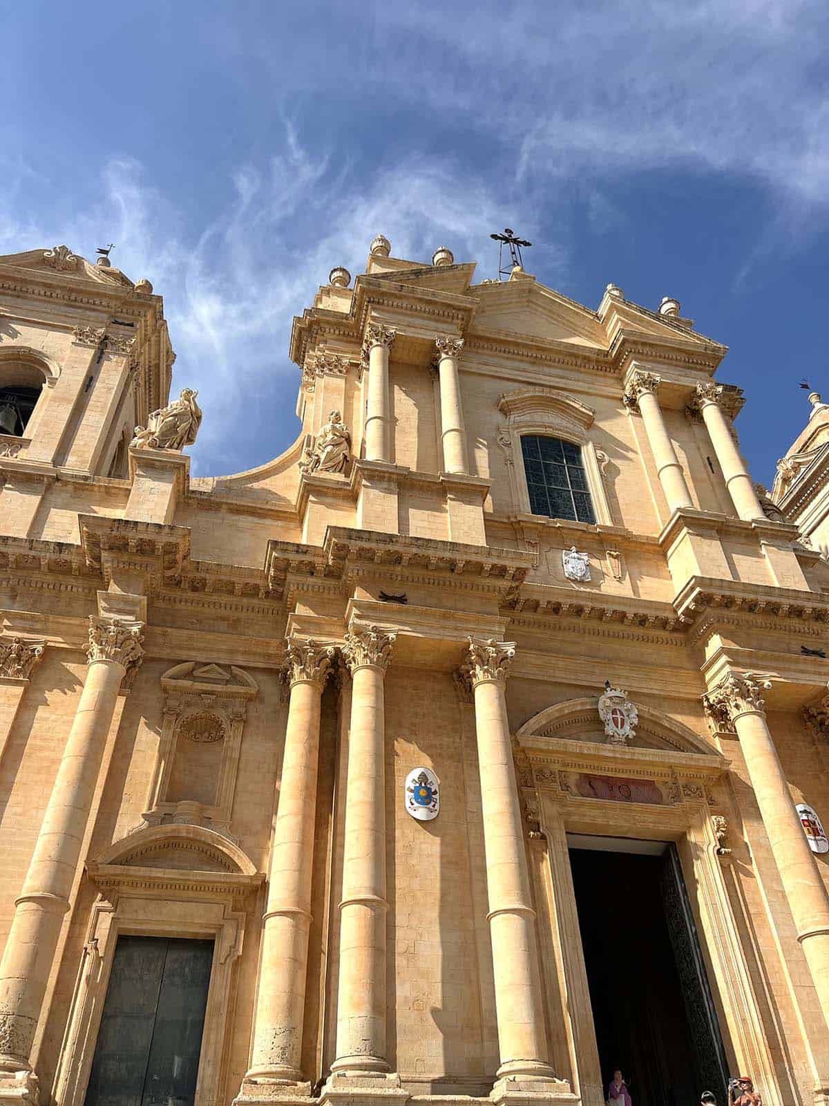 An image of a rustic building in Noto, Sicily, with a blue sky as a backdrop