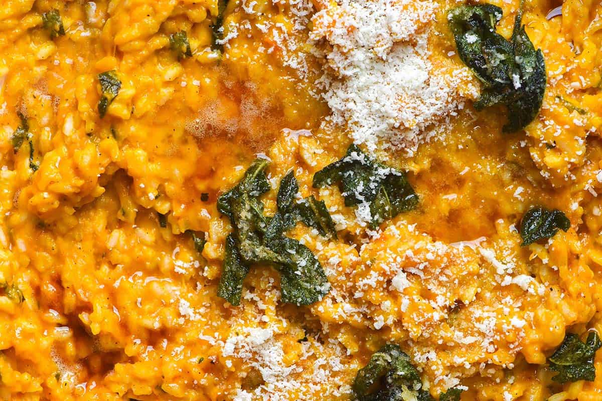 A close up macro image of pumpkin risotto topped with brown sage butter and finely grated parmesan