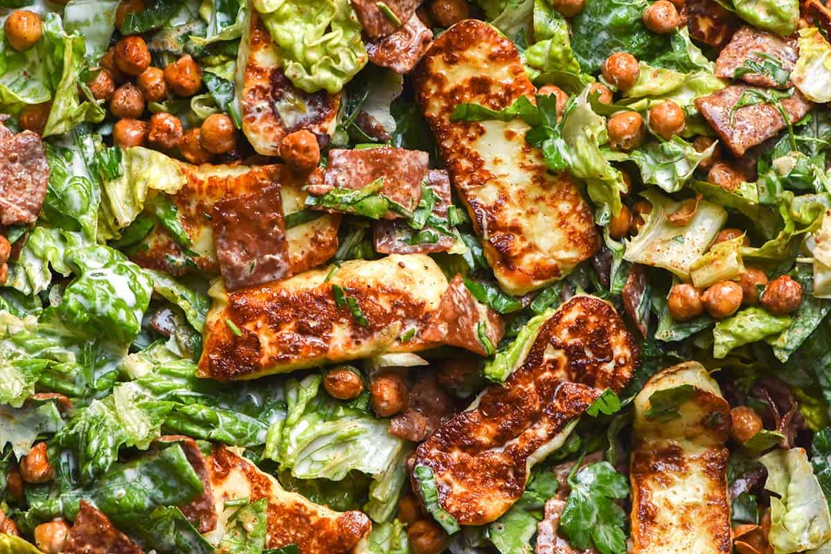 An aerial macro image of a haloumi salad with vegetarian bacon, crispy chickpeas and a creamy caper salad dressing. 
