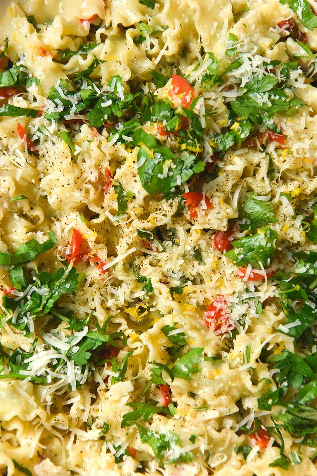 A close up aerial image of low FODMAP pasta topped with parsley, chilli, lemon zest and chilli. 