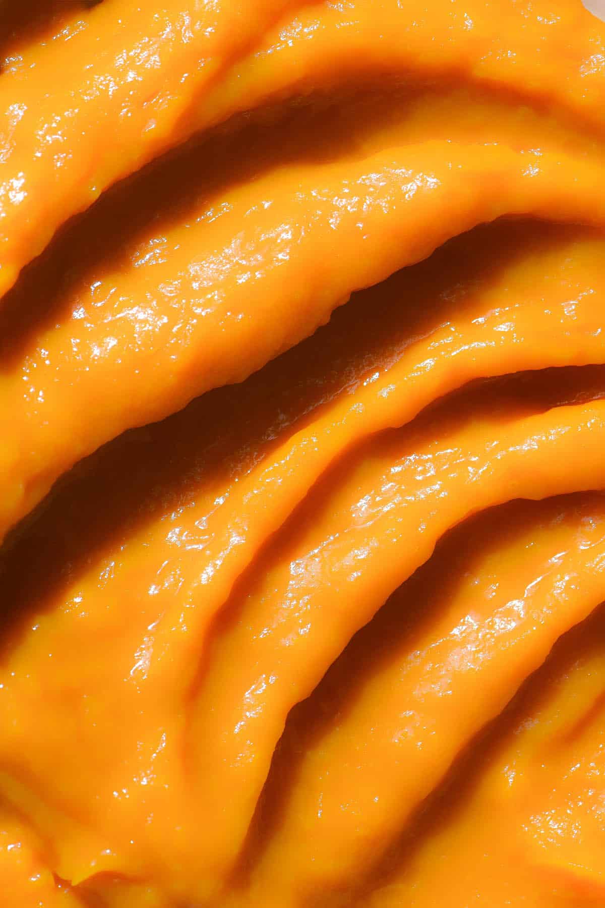 An aerial macro image of a bowl of pumpkin puree arranged in a swirl pattern