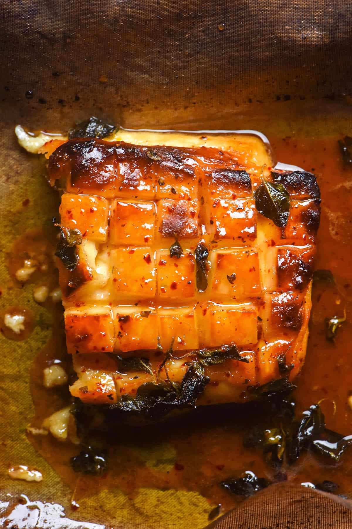 An aerial image of a golden brown, scored and baked slab of halloumi with a maple syrup, lemon and herb glaze.