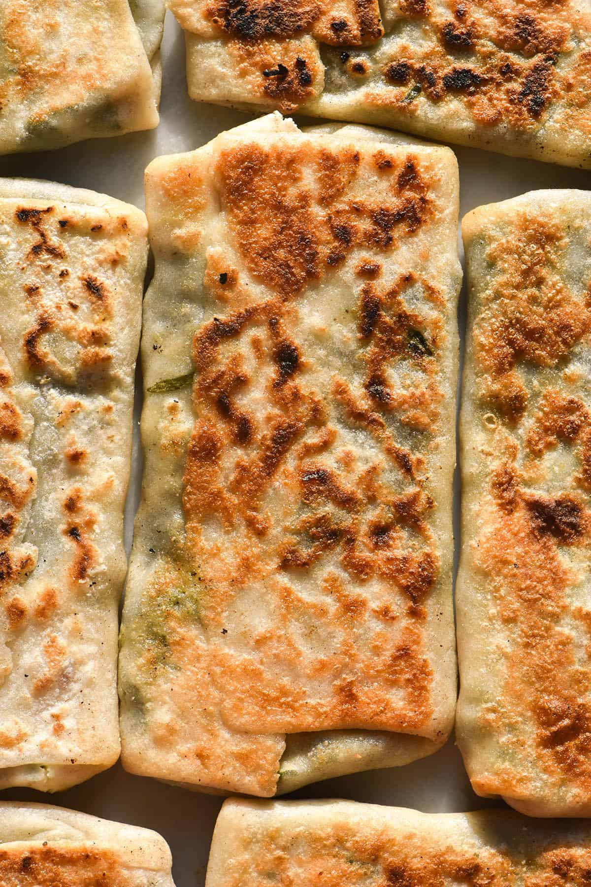 A sunlit aerial macro image of gluten free spinach and feta gozleme on a white marble table