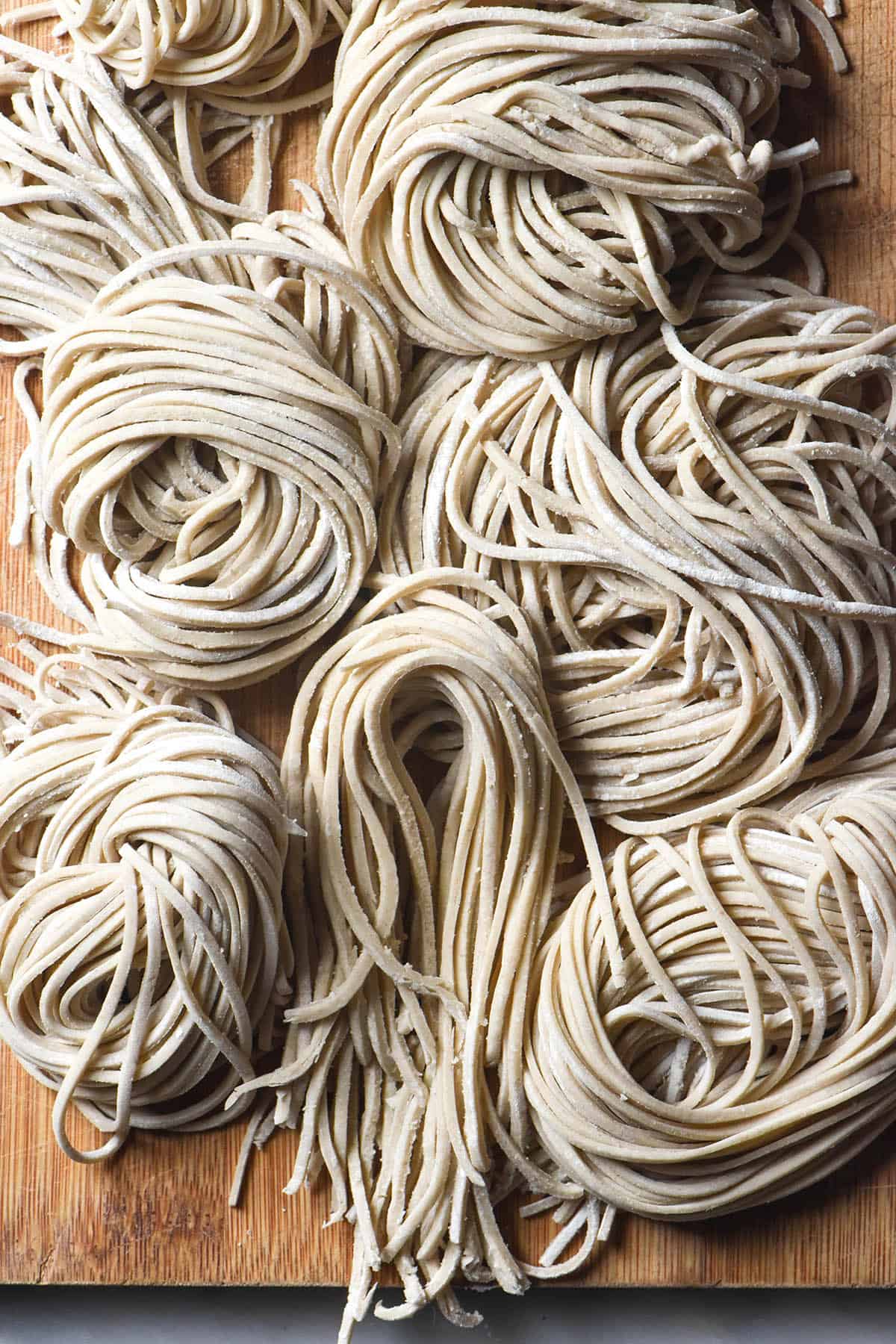 An aerial image of nests of gluten free soba noodles casually arranged on a wooden backdrop