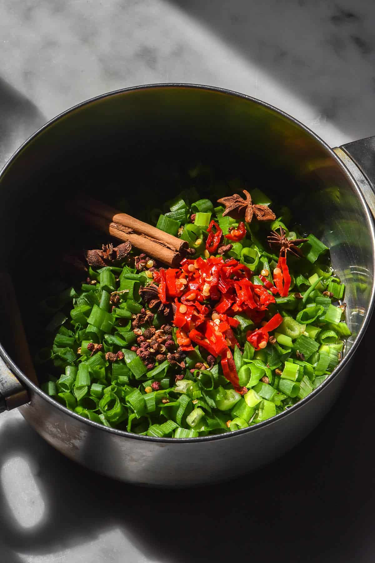 An image of a saucepan filled with the ingredients used to make a low FODMAP chilli crisp. 