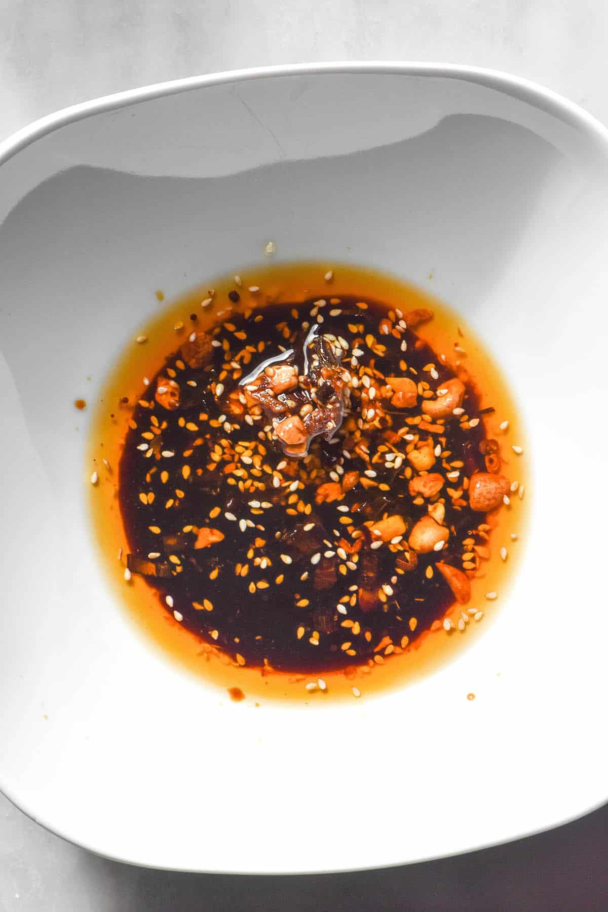 An aerial image of low FODMAP dumpling sauce in a white bowl atop a white marble table