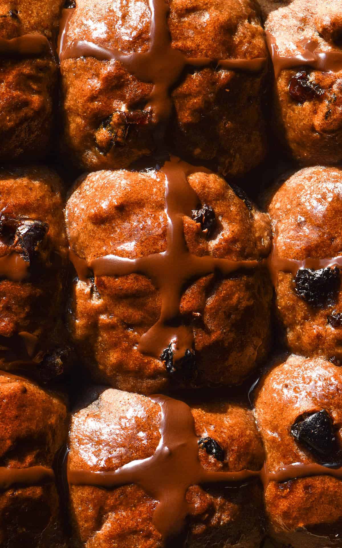 An aerial macro close up of a tray of gluten free hot cross buns with chocolate crosses