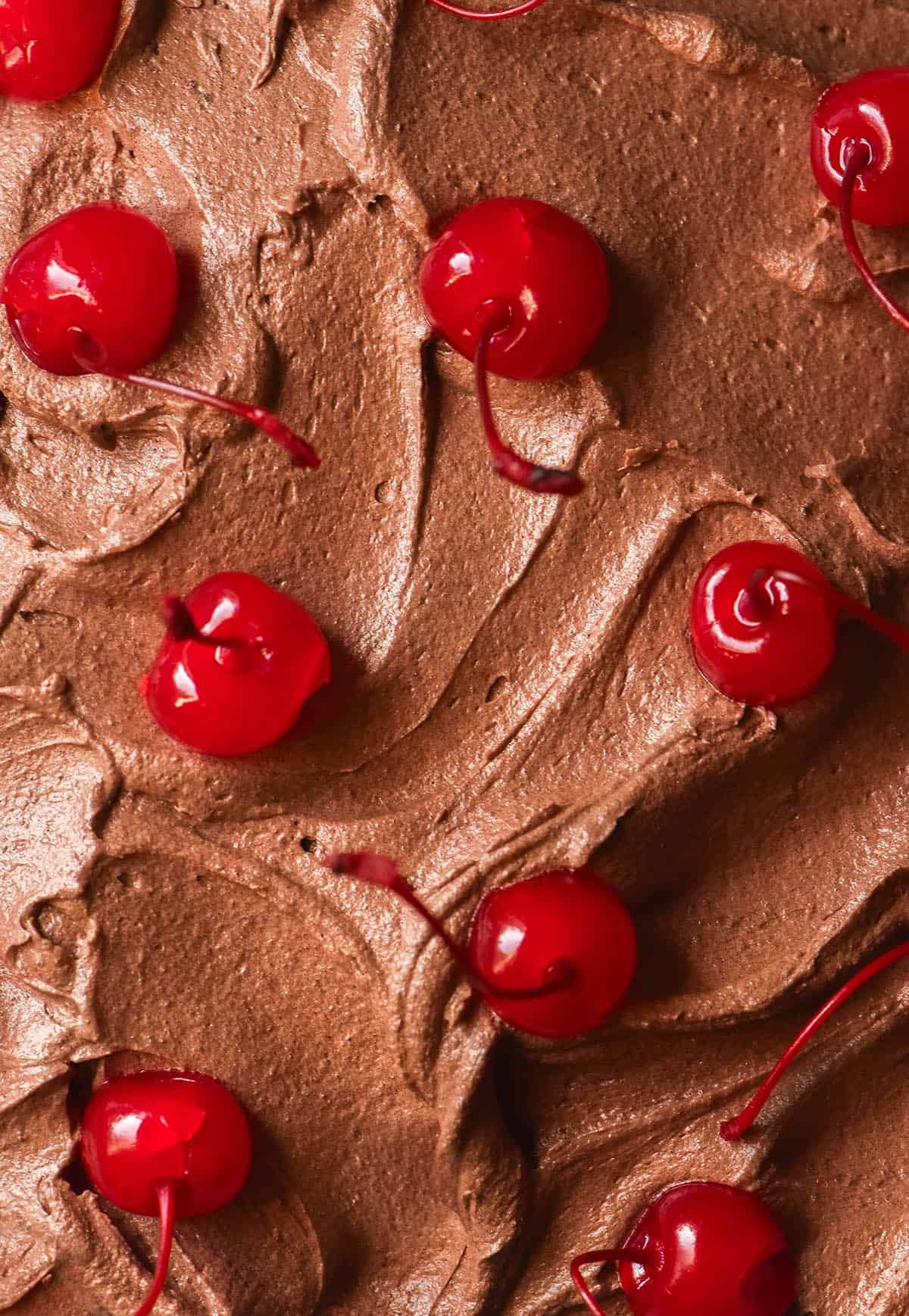 A maco aerial image of swirly dairy free chocolate buttercream topped with maraschino cherries
