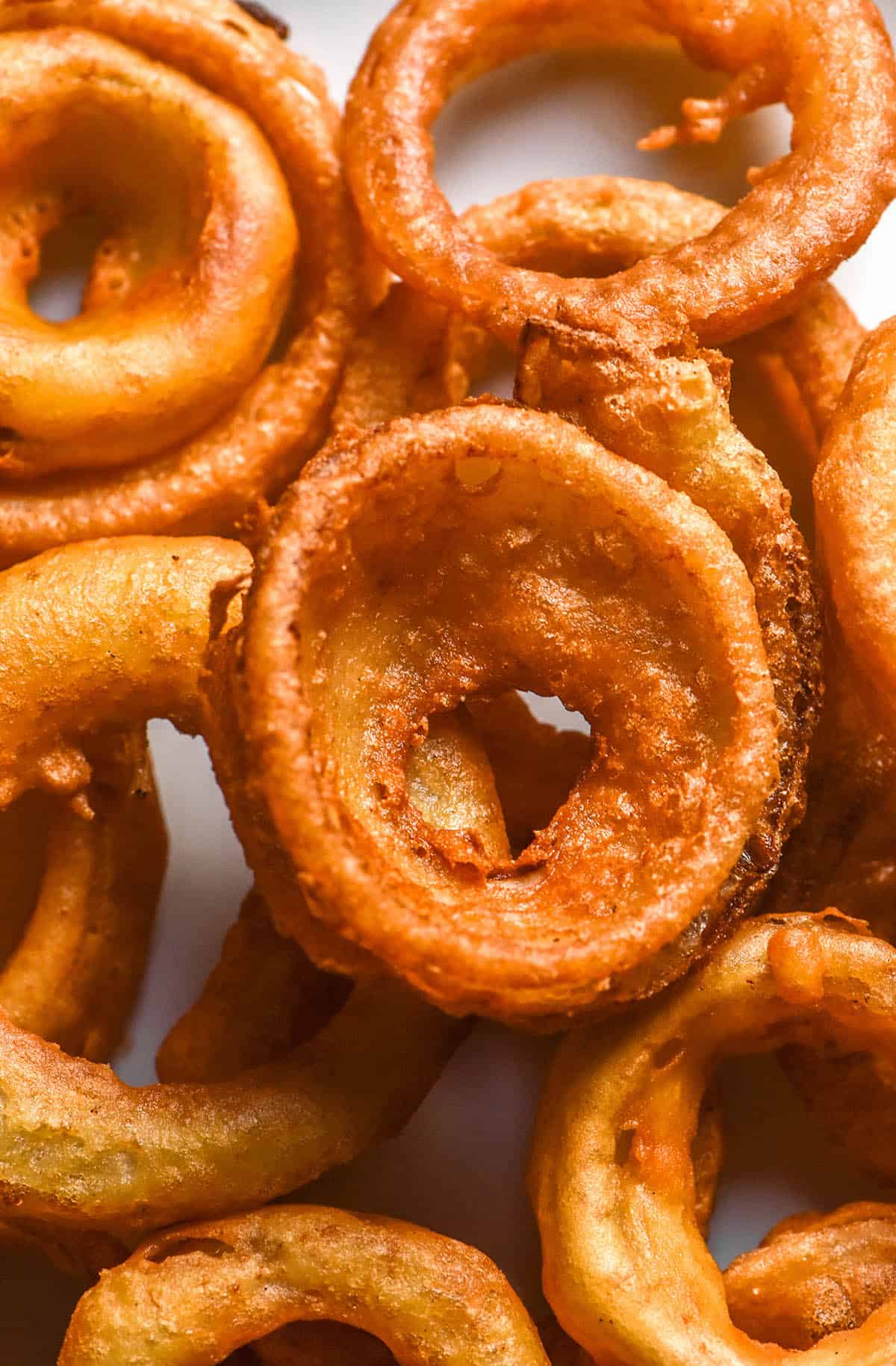An aerial image of gluten free onion rings on a white plate atop a white marble table