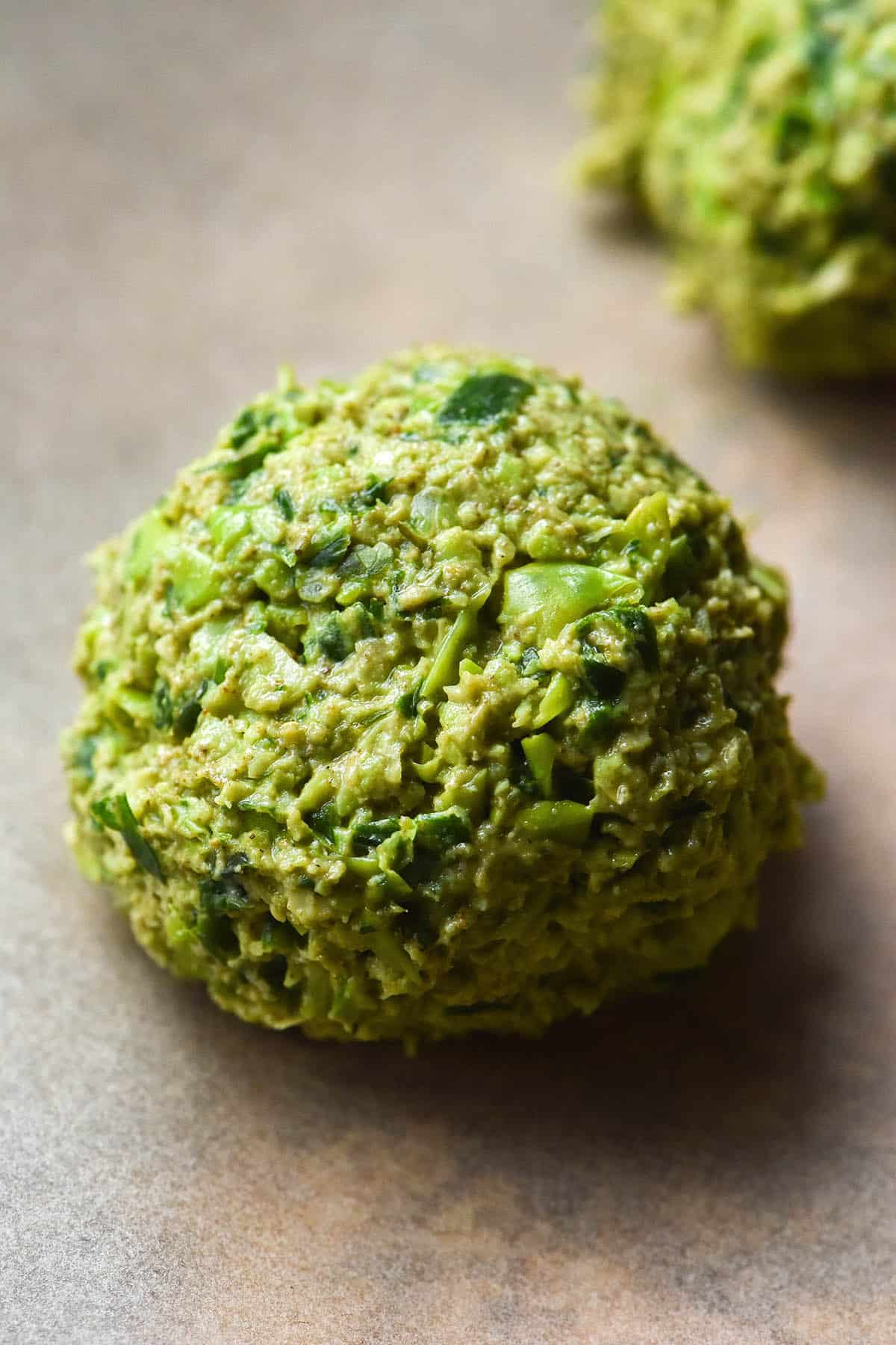 A macro image of a bright green uncooked falafel