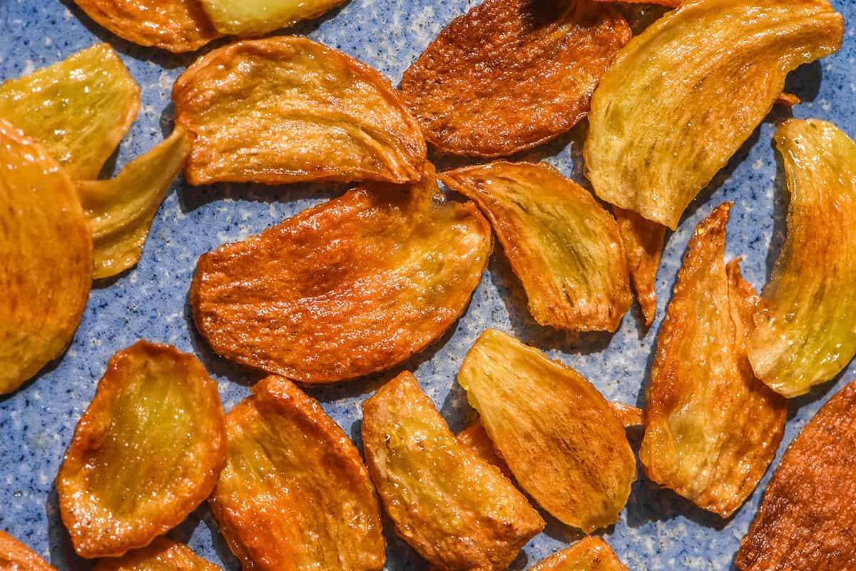 A brightly lit aerial image of golden brown low FODMAP garlic chips on a bright blue ceramic plate