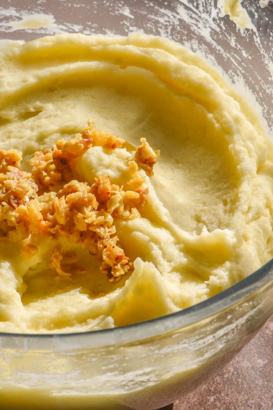 A side on image of a glass bowl filled with low FODMAP garlic mashed potatoes