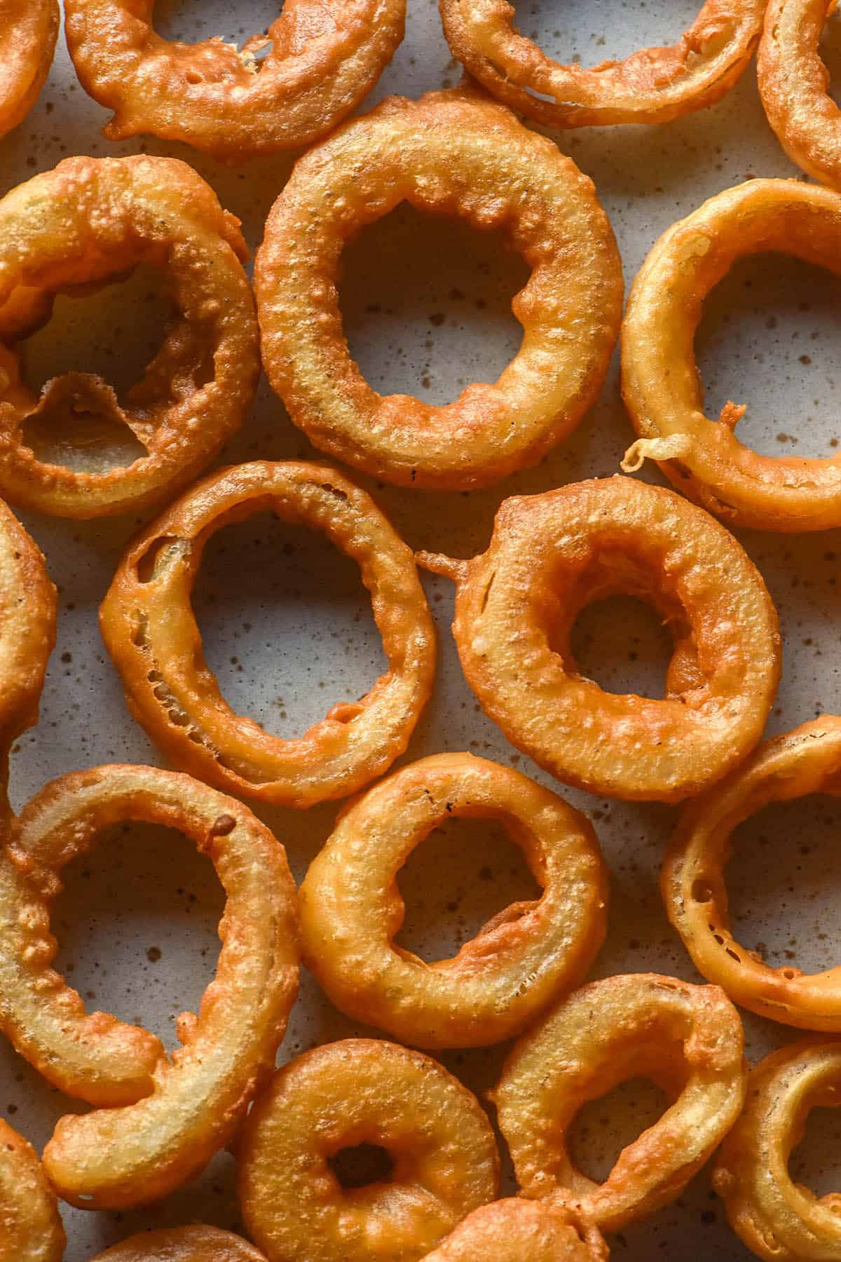 An aerial image of low FODMAP onion rings casually arranged on a white plate