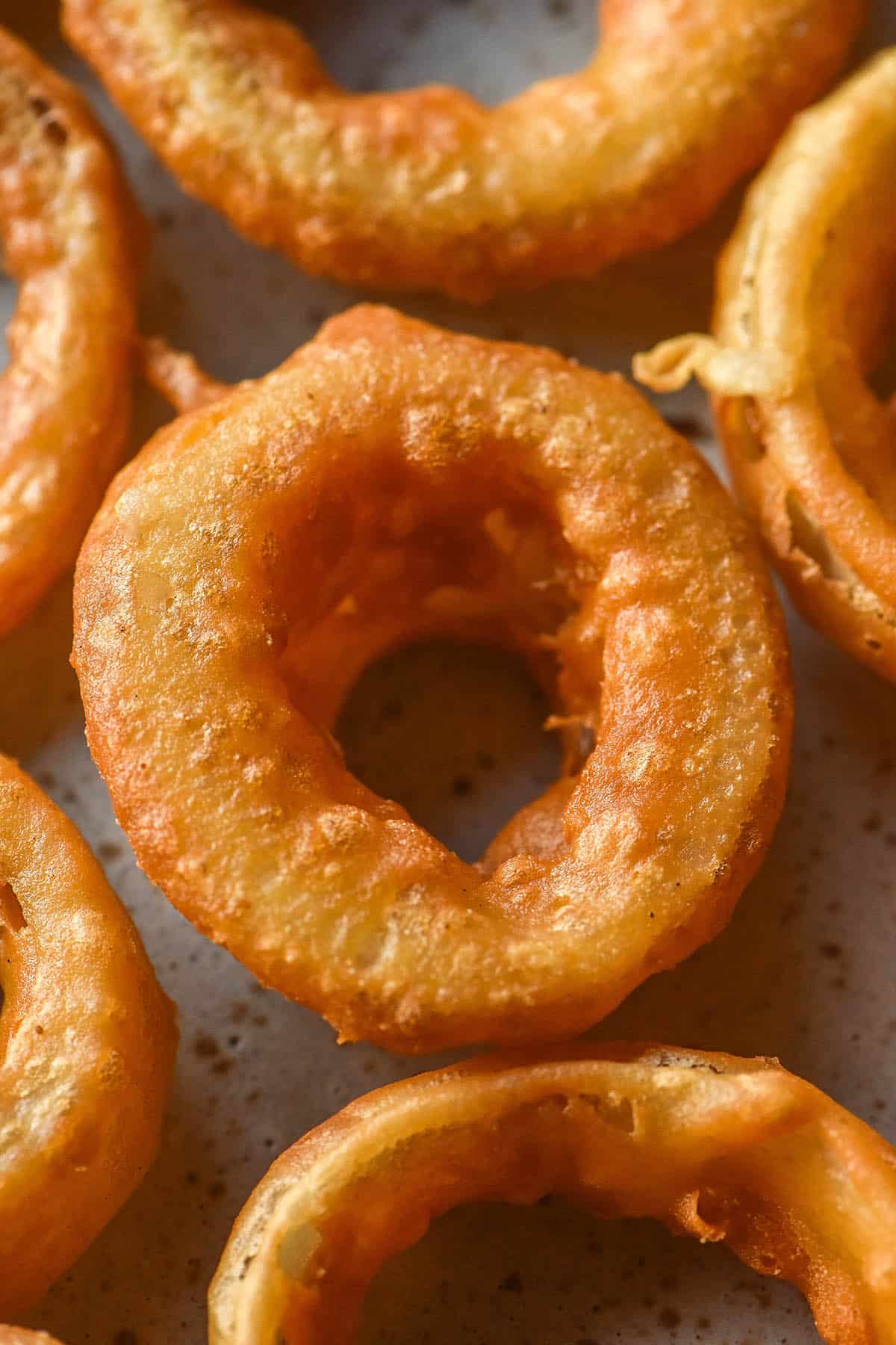A close up macro image of low FODMAP onion rings on a white plate