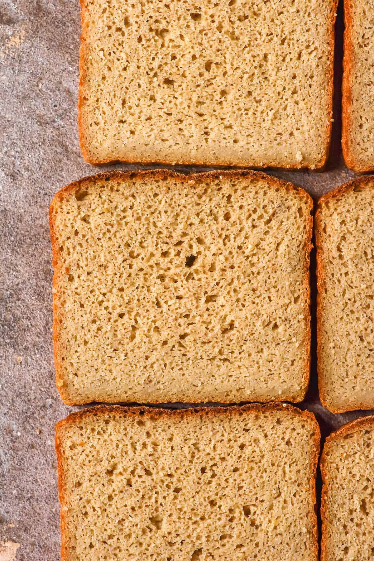 An aerial image of slices of gluten free quinoa bread arranged on a grey backdrop