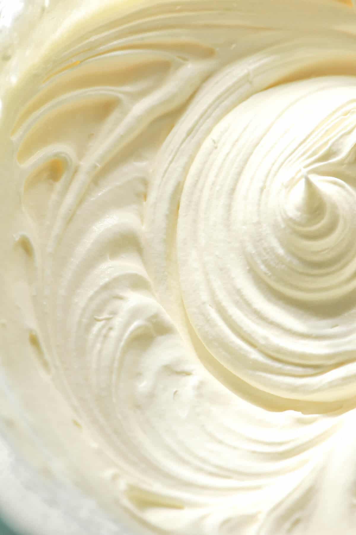 A macro aerial image of lactose free whipping cream in a glass bowl