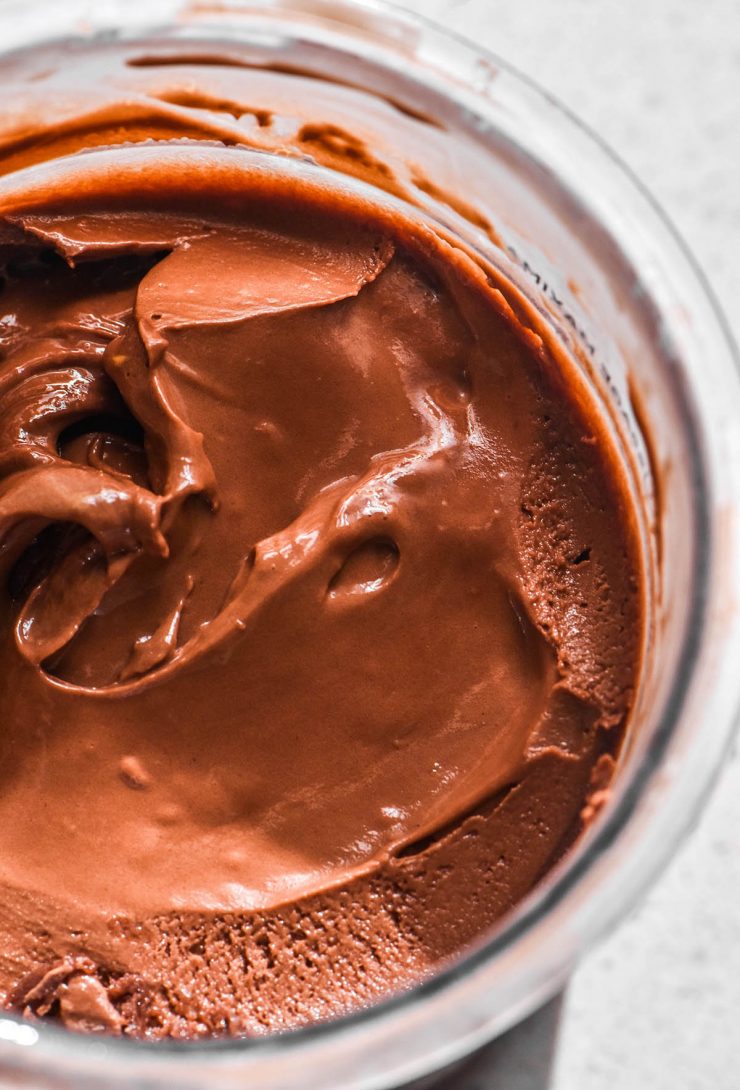 An aerial macro image of a tub of Ninja Creami chocolate ice cream on a white stone bench top