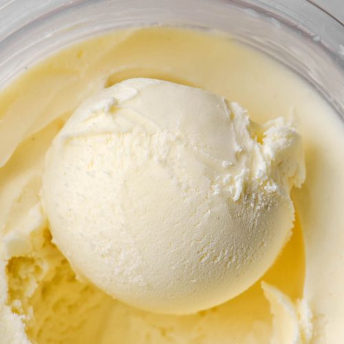 An aerial image of a tub of vegan vanilla Ninja Creami ice cream atop a white marble table