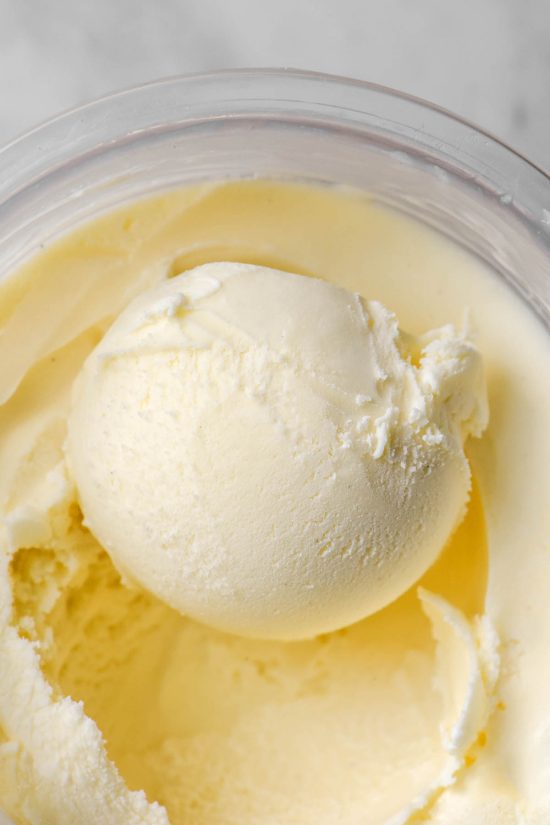 An aerial image of a tub of vegan vanilla Ninja Creami ice cream atop a white marble table