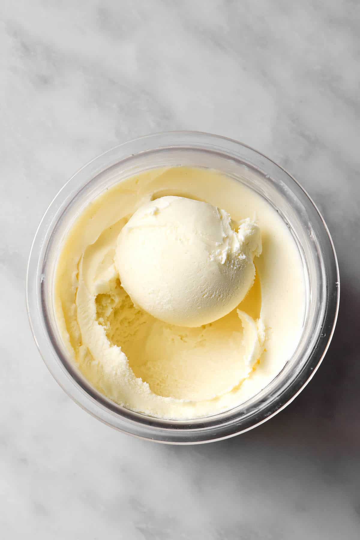 An aerial image of a tub of Ninja Creami vegan vanilla ice cream atop a white marble table