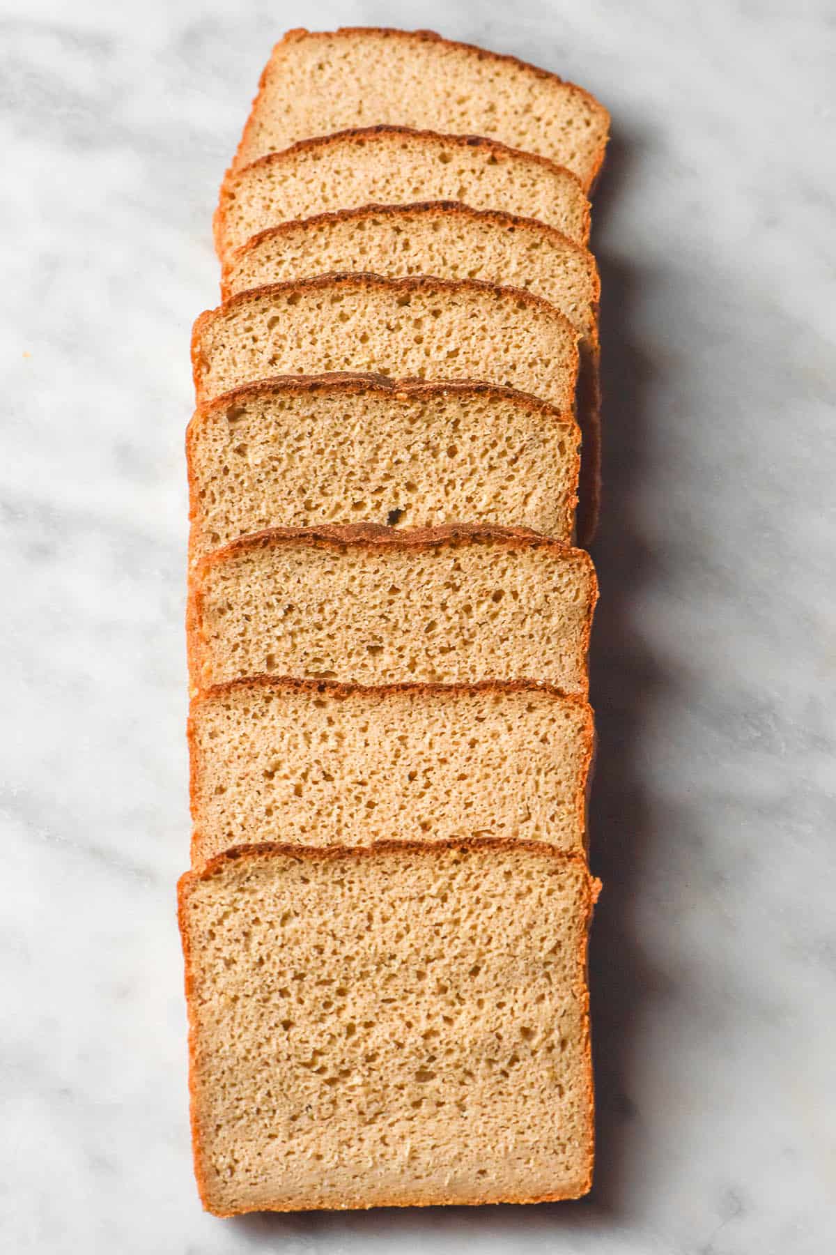 An aerial image of slices of quinoa bread arranged in a line on a white marble table