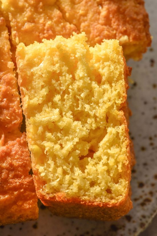 An aerial close up image of a slice of cornbread on a white speckled ceramic plate