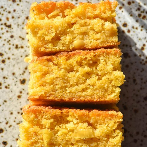 An aerial image of a stack of slices of gluten free cornbread on a white speckled ceramic plate