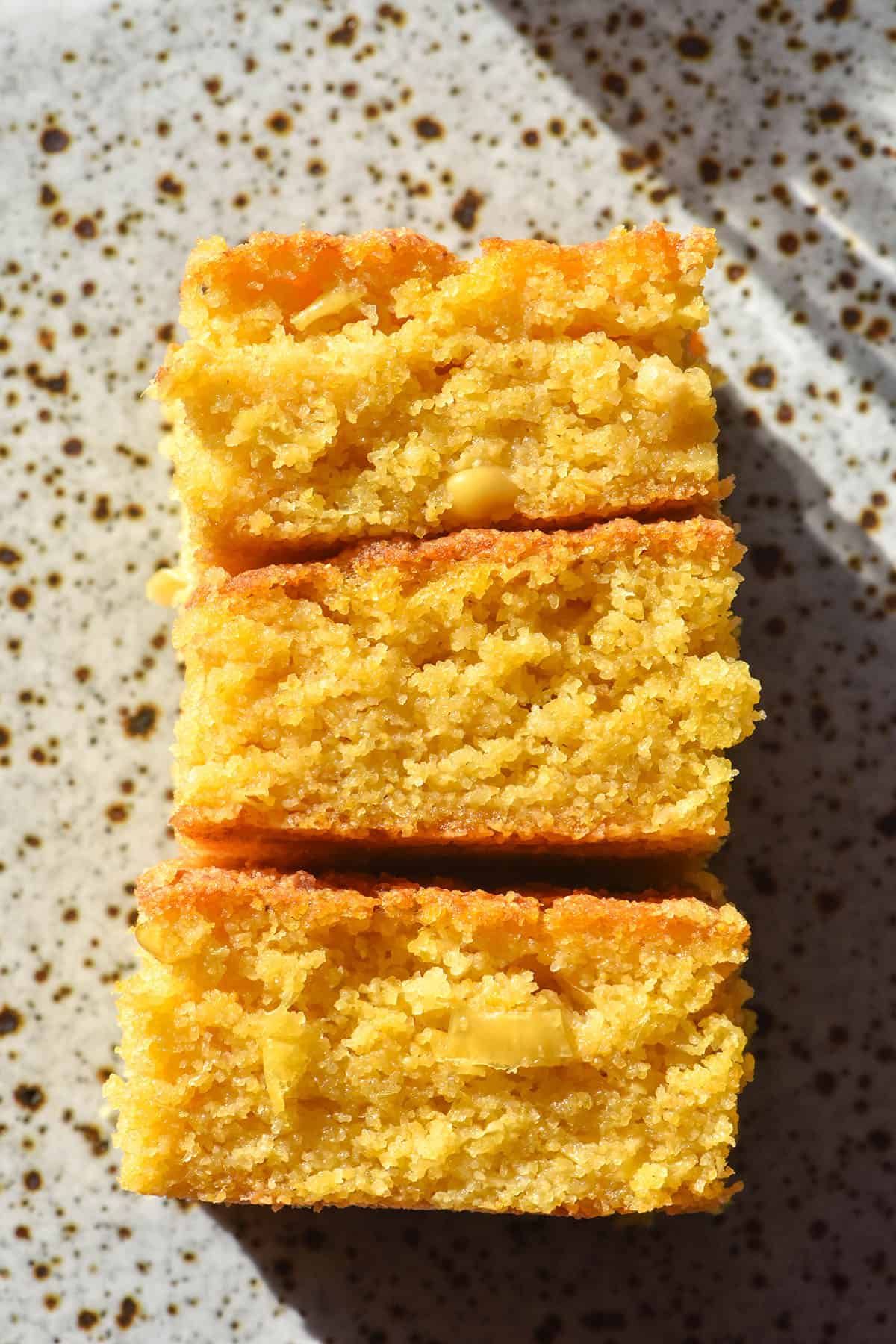 An aerial image of a stack of slices of gluten free cornbread on a white speckled ceramic plate