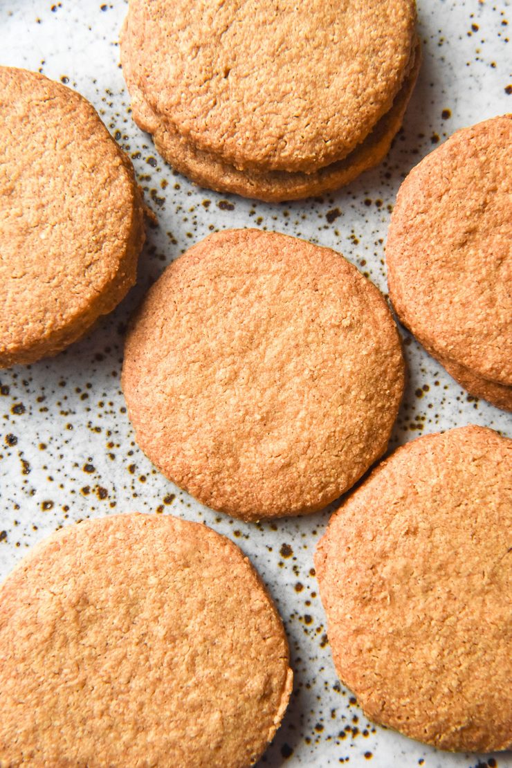 An aerial image of gluten free digestive biscuits arranged casually on a white speckled ceramic plate