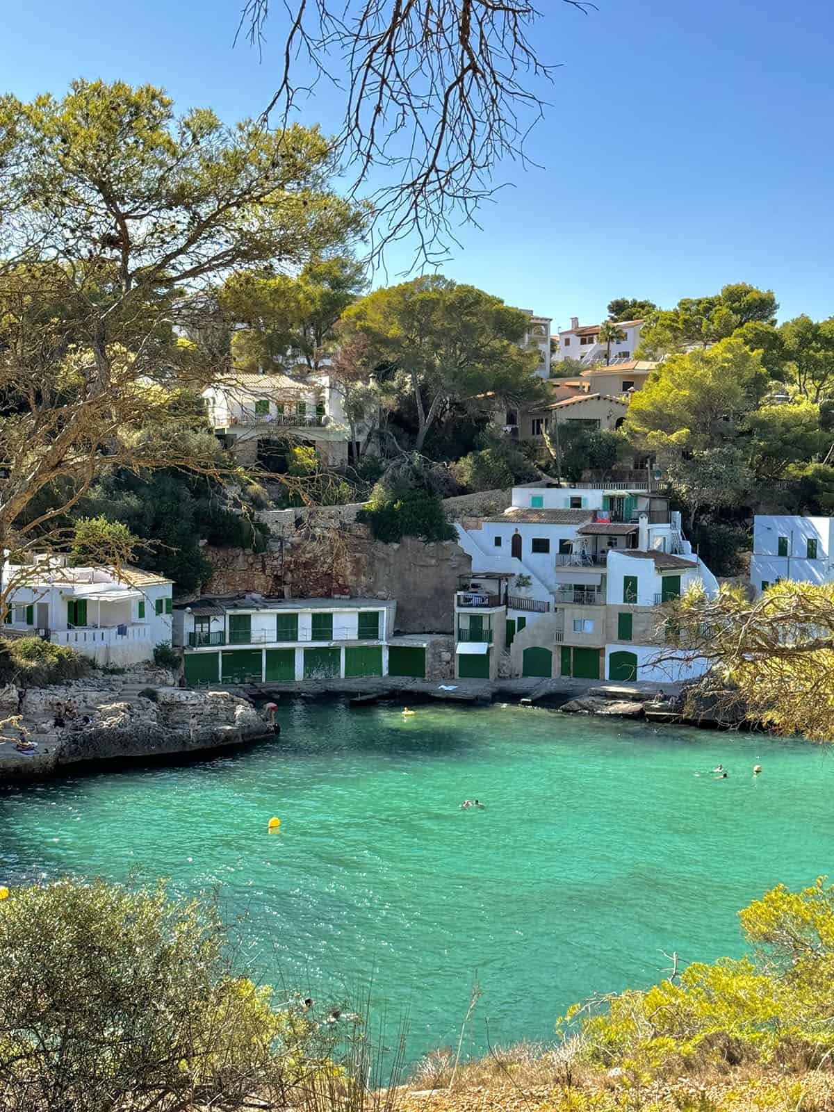 A view of the bright blue water and fishermen's houses at Cala Santanyi, Mallorca