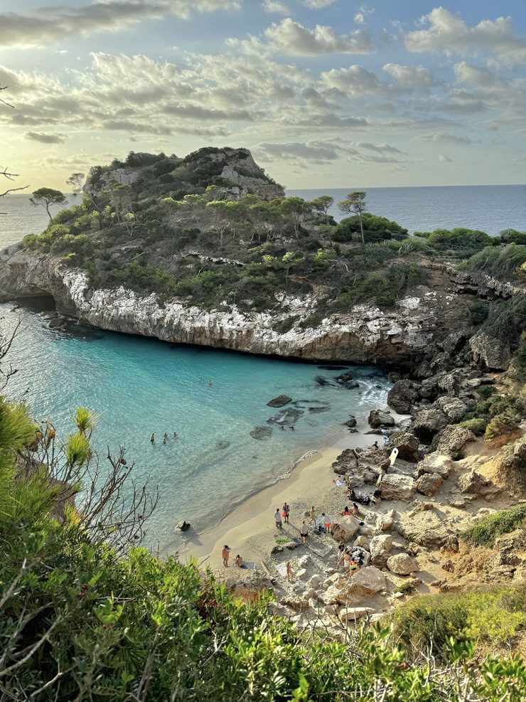 An image of Calo Des Moro beach in Mallorca which captures the surrounding cliffs and sunny skies