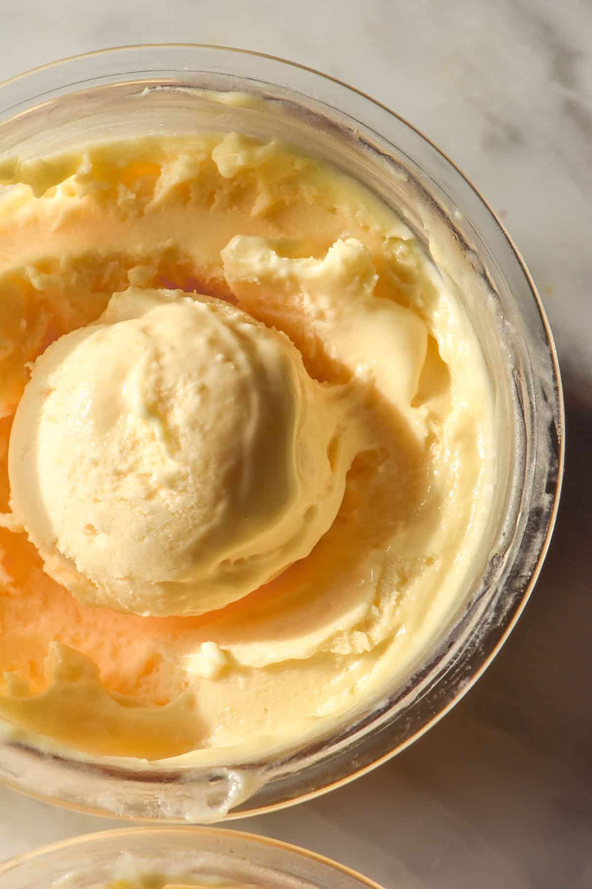 An aerial macro image of a tub of Ninja Creami lemon curd ice cream on a white marble table