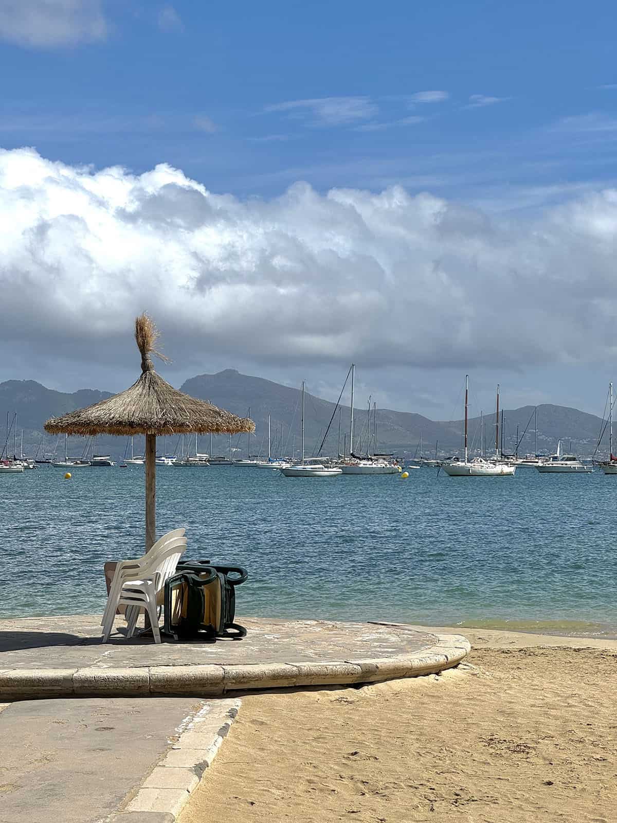 An image of a thatched beach umbrella in the early morning at Port De Pollenca beach in Mallorca