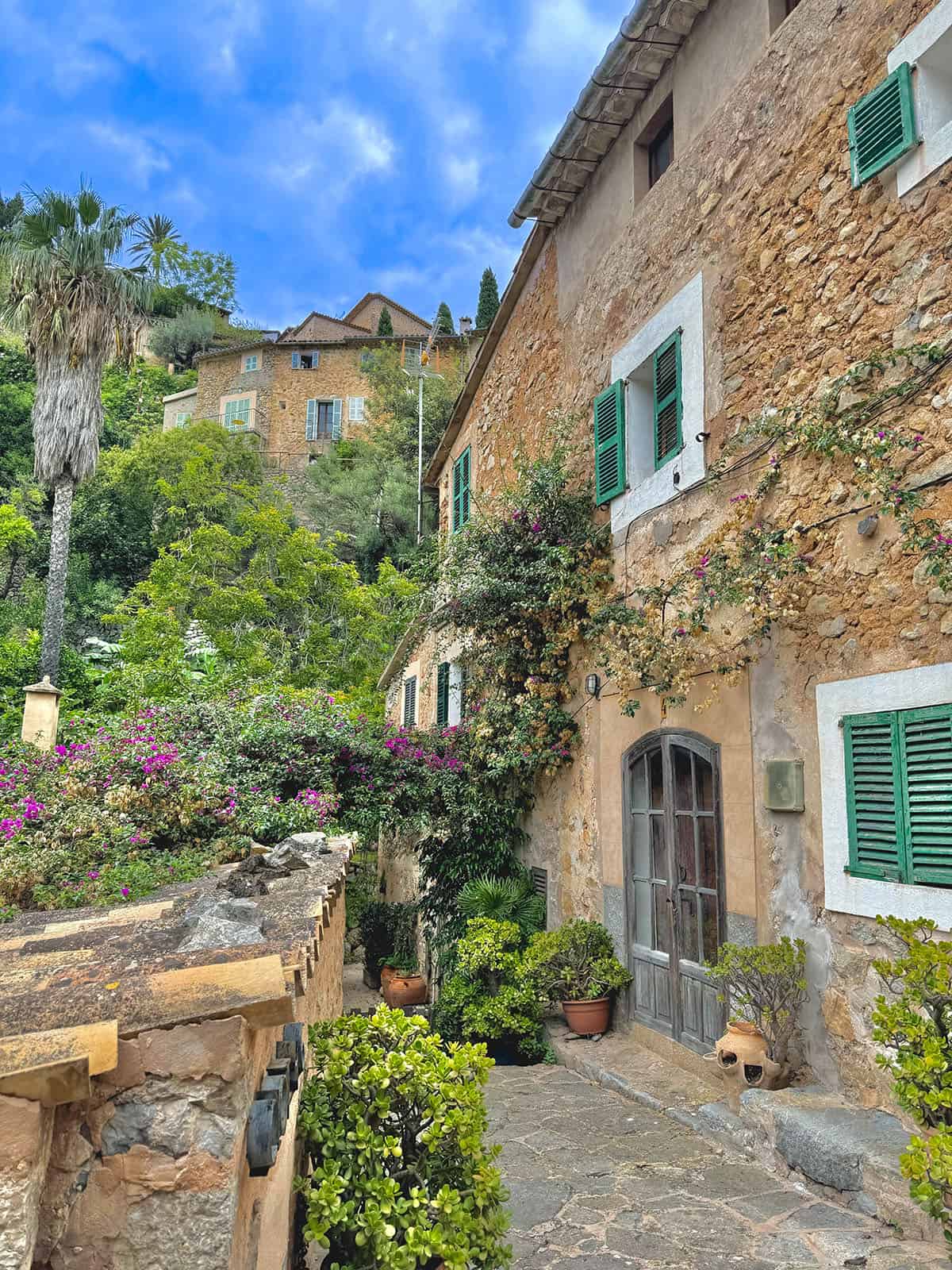 A view of a house and the garden in Deia, Mallorca, on a sunny day with blue skies