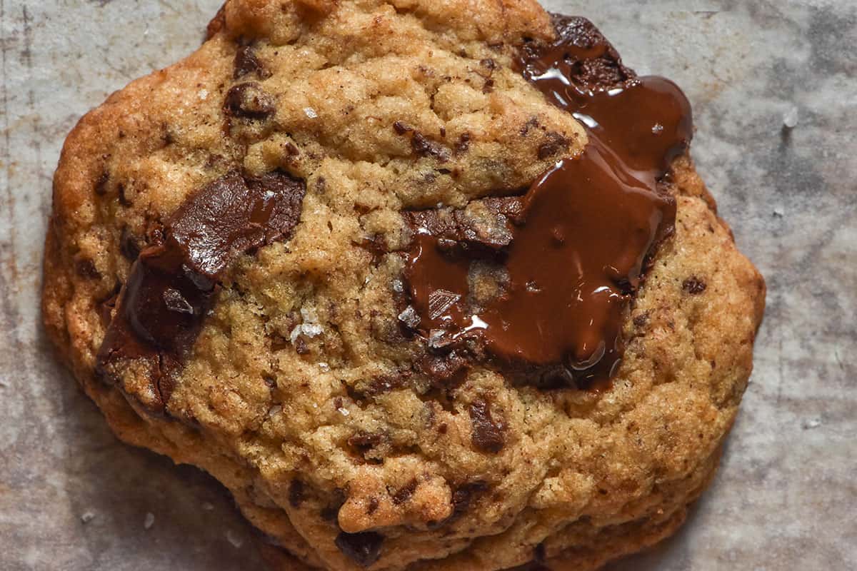 A macro aerial image of a gluten free banana cookie with molten chocolate chunks and a sprinkling of sea salt flakes