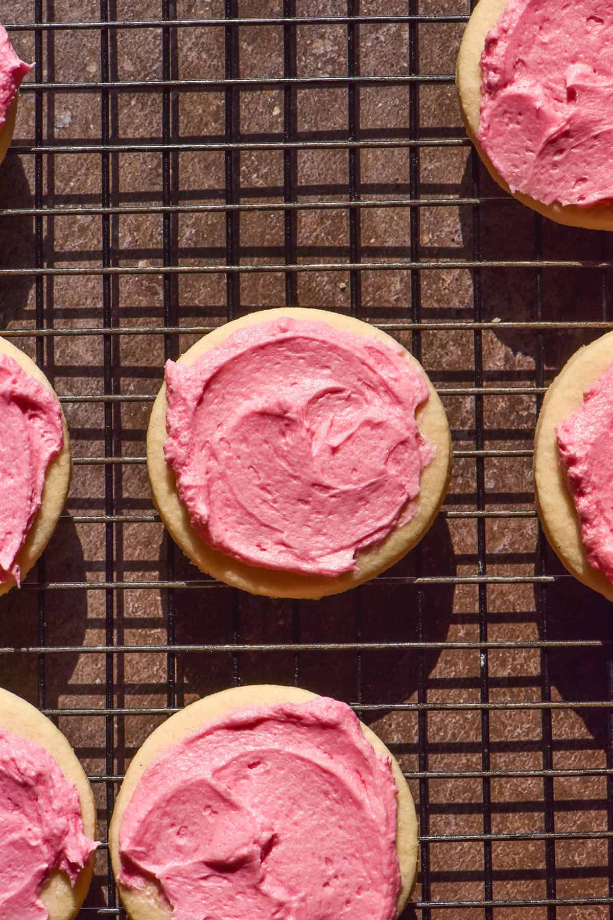 A brightly lit aerial image of gluten free Lofthouse cookies on a cooling rack atop a dark grey brown backdrop